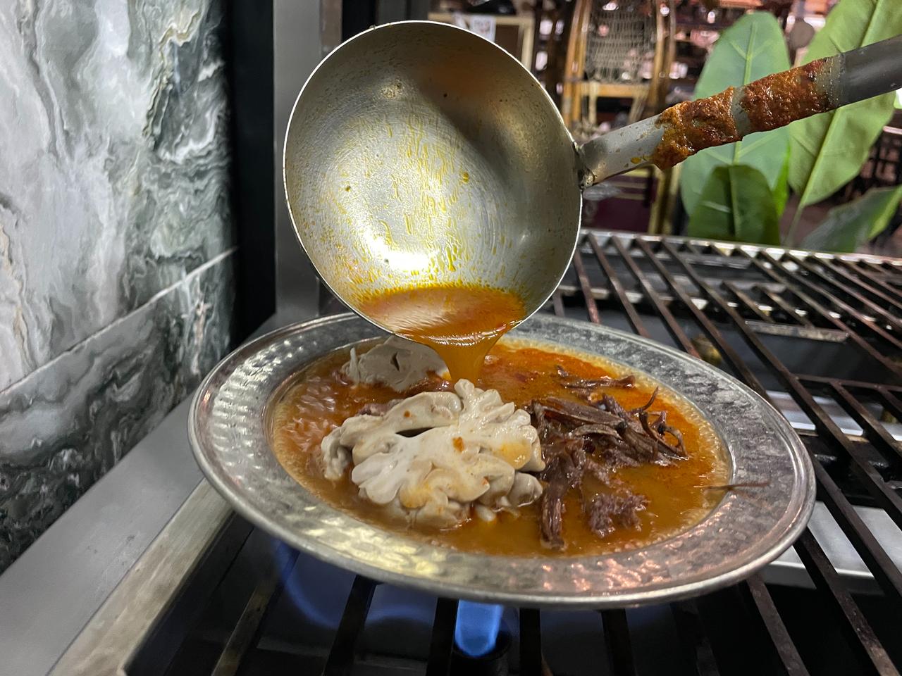 Hot broth is poured over brain and shredded offal during the preparation of Konya's "atom" soup. (IHA Photo)
