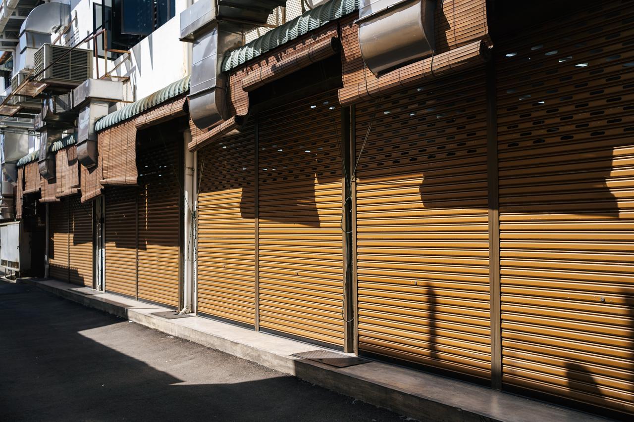 Closed storefronts with metal shutters illustrate pressures facing businesses and the retail sector. (Adobe Stock Photo)