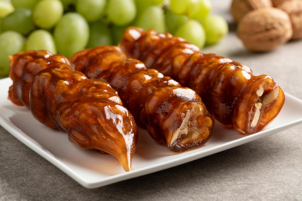Walnuts encased in hardened grape molasses form the distinctive shape of traditional walnut sucuk. (Adobe Stock Photo)