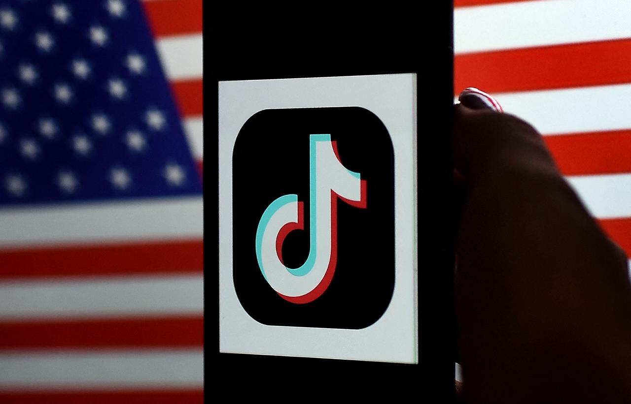 In this photo illustration, the social media application logo, TikTok is displayed on the screen of an iPhone on a US flag background in Arlington, Virginia on August 3, 2020. (AFP Photo)