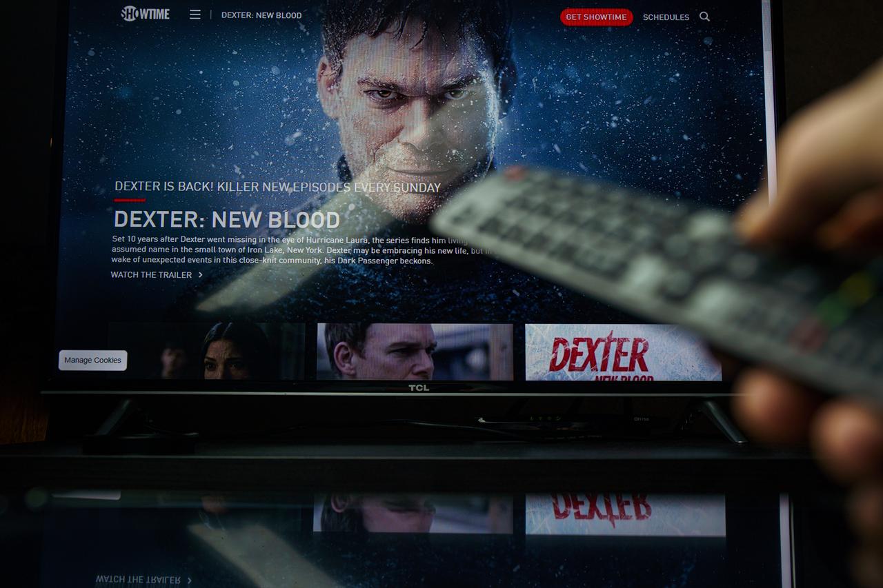 A television screen displays promotional material for Dexter: New Blood on Showtime as a viewer holds a remote control. (Adobe Stock Photo)