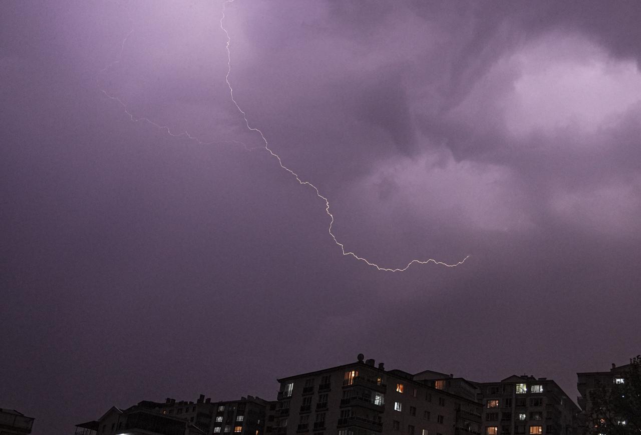 A bright bolt of lightning illuminates the purple-hued stormy sky above a residential area in Istanbul. (AA Photo)