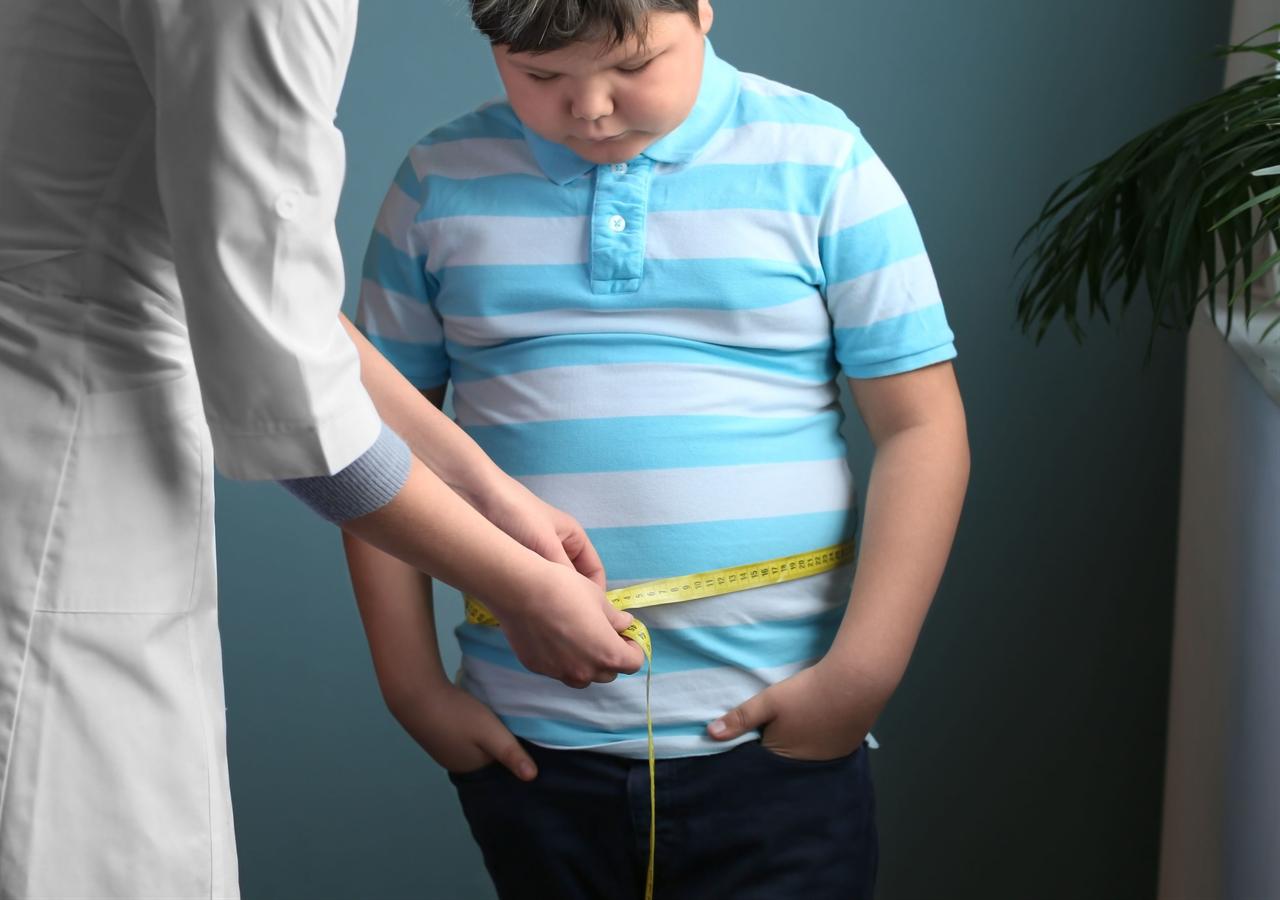 A health professional measures a child’s waist with a tape measure during a weight assessment. (Adobe Stock Photo)