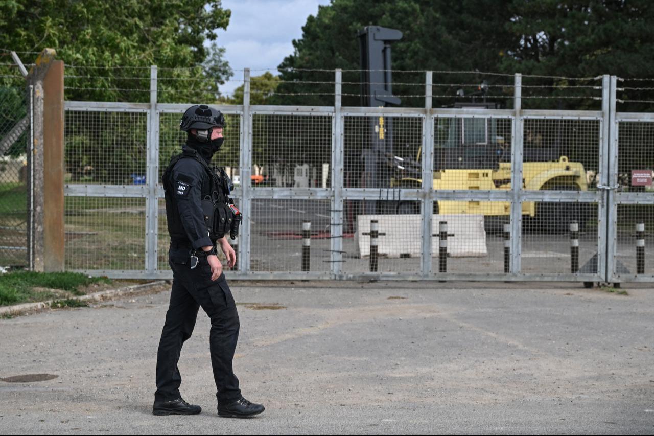 A masked policeman guards an entrance to RAF Fairford base, blocked by heavy machinery (back R) inside the gate, in Fairford, south-west England, Sept. 27, 2026. (AFP Photo)