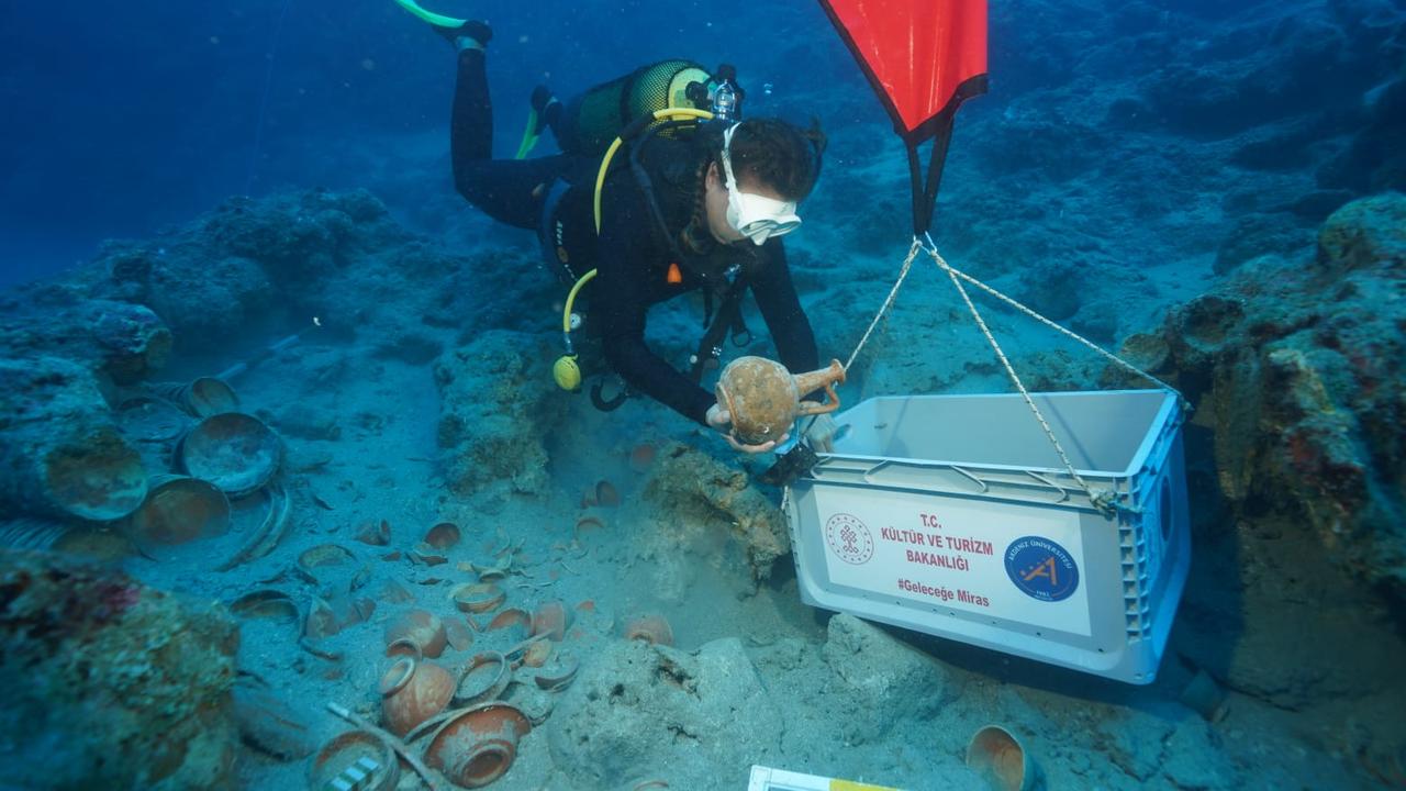 An underwater archaeologist carefully places a ceramic vessel recovered from the 2,100-year-old Adrasan shipwreck into a container during excavation work. (AA Photo)