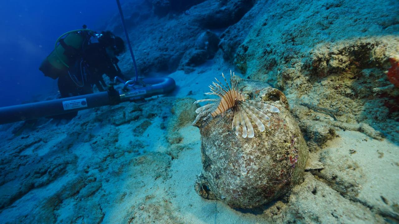 A lionfish rests on an ancient ceramic vessel as an archaeologist carries out underwater excavation work at the shipwreck off Antalya. (AA Photo)