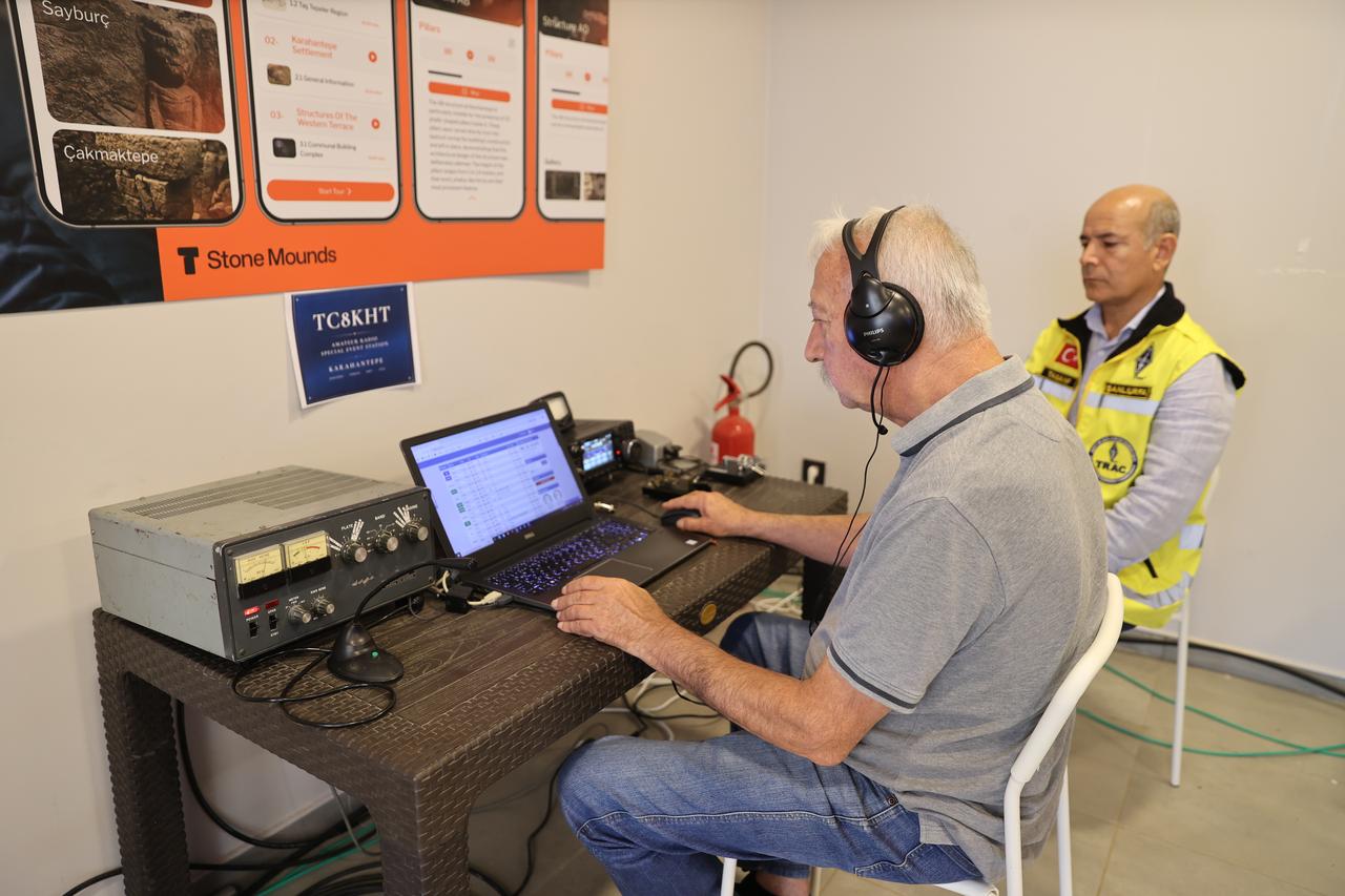 An amateur radio operator works alongside a TRAC member at a station set up inside the Karahantepe Welcome Center in Sanliurfa, Türkiye. (AA Photo)