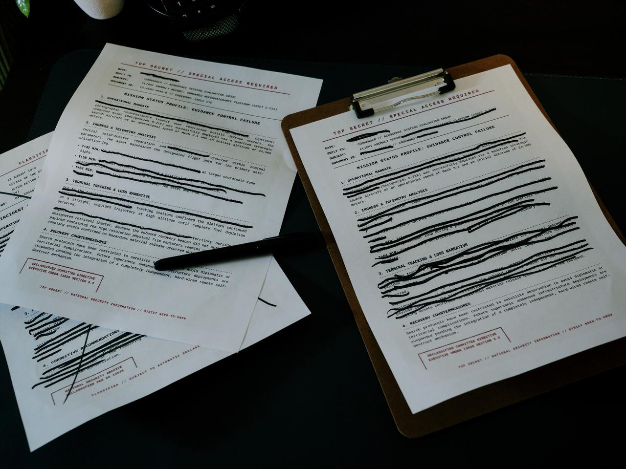 Redacted documents marked “Top Secret” are arranged on a desk, illustrating classified or confidential information, undated. (Adobe Stock Photo)