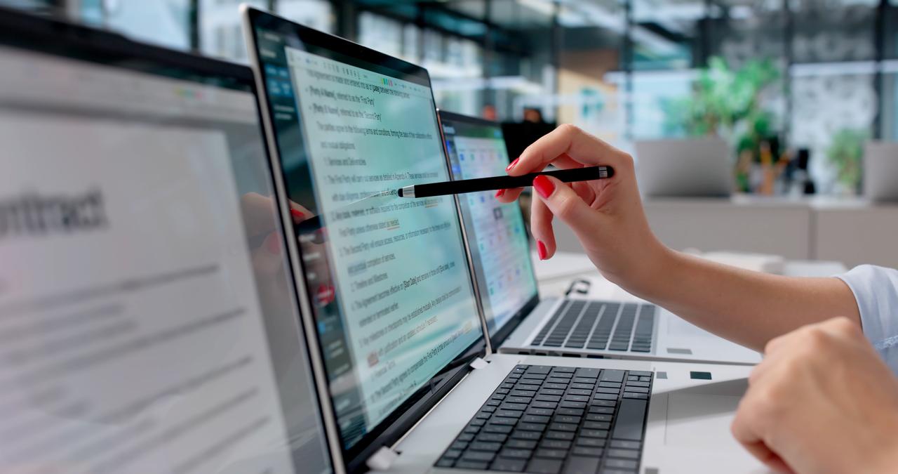 A person reviews and edits text on a laptop in an office setting, undated. (Adobe Stock Photo)