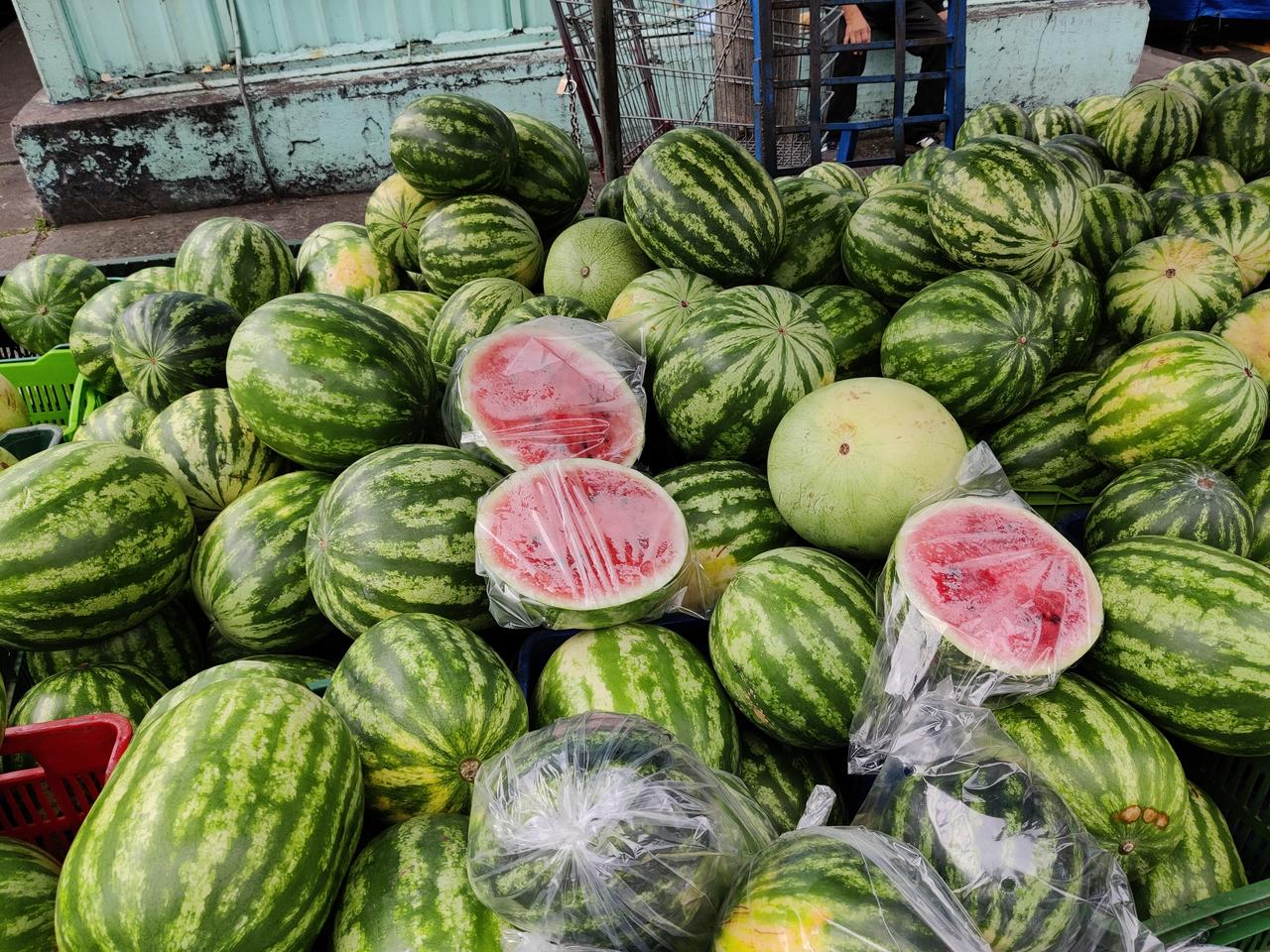 Watermelons, including several cut open to show their red flesh, are displayed for sale at a market, undated. (Adobe Stock Photo)