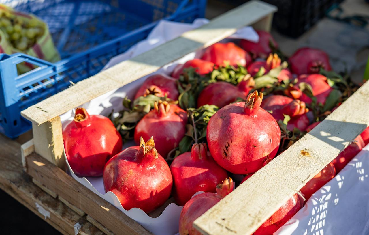Fresh pomegranates are displayed in wooden crates at a market stall. (Adobe Stock Photo)