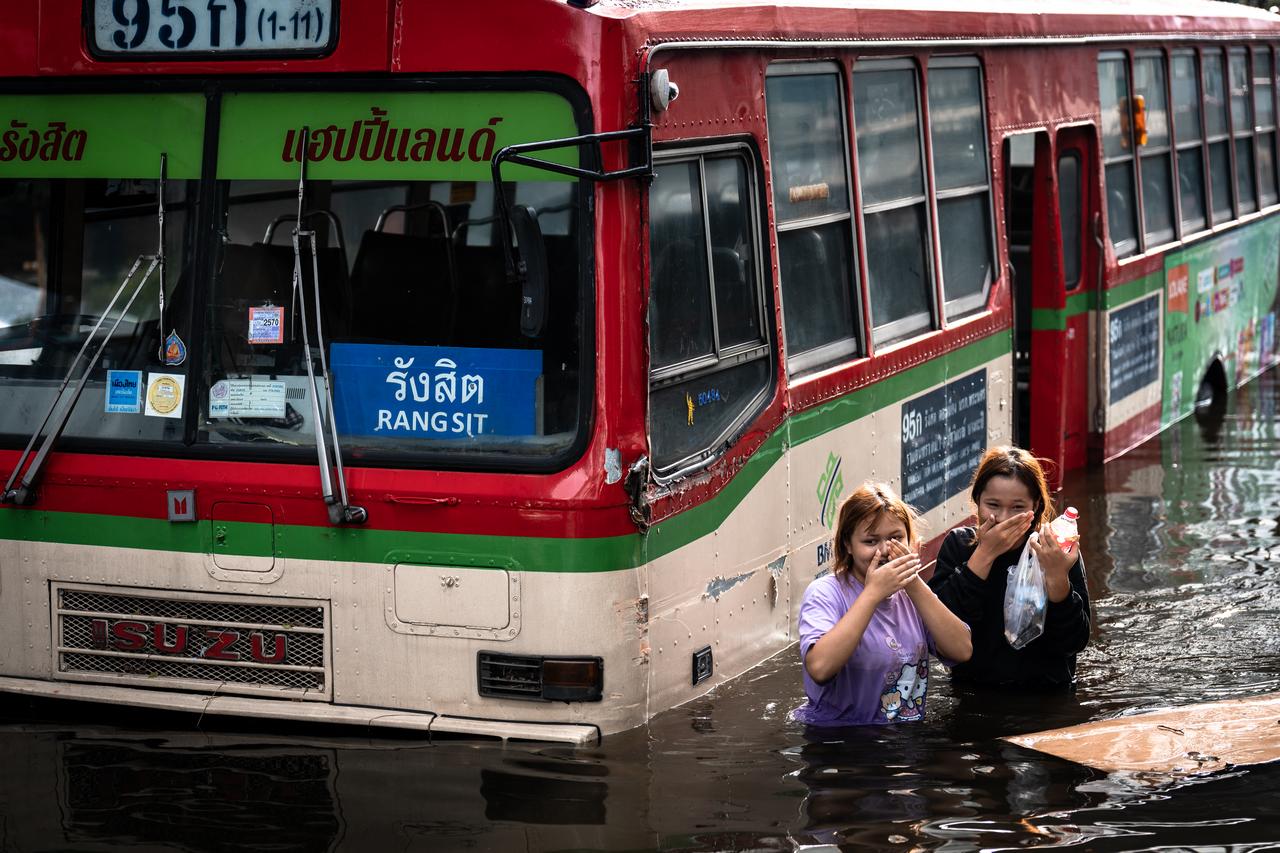 Women walk past an abandoned bus in the Bang Kapi district of Bangkok on Sept. 28, 2026. (AFP Photo)