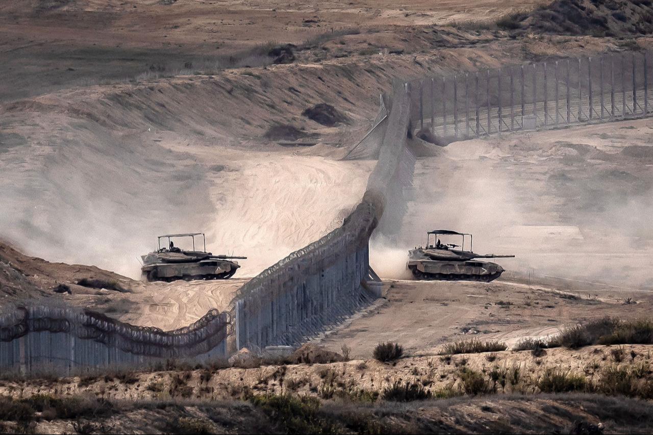 Israeli tanks cross a barbed wire fence at a position along the border with the Gaza Strip and southern Israel on November 12, 2023. (AFP Photo)