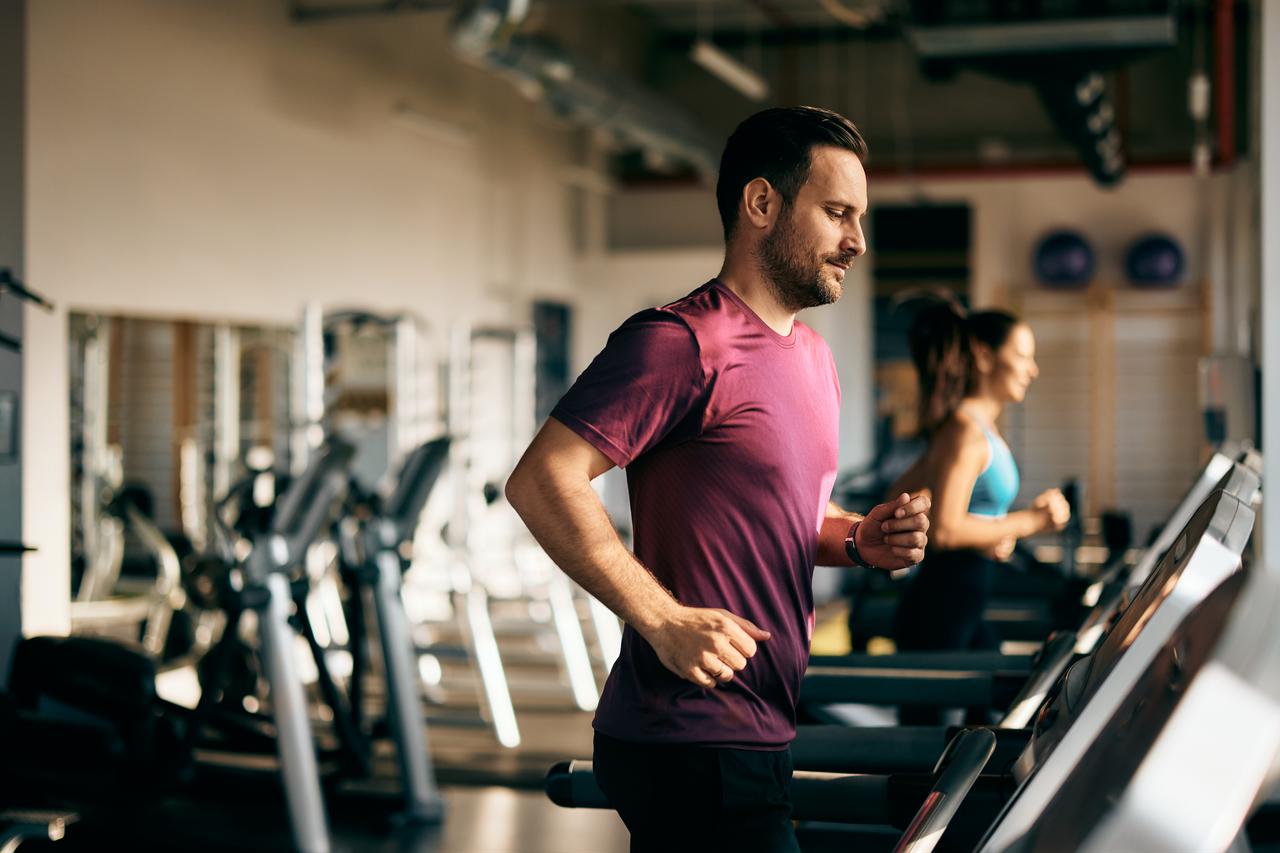 1. A man runs on a treadmill at a gym as another person exercises in the background, illustrating indoor fitness training. (Adobe Stock Photo)