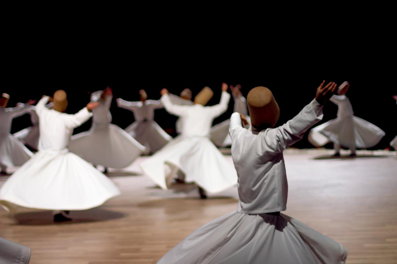 Dervish performance on a wooden stage. (Photo via Adobe Stock)
