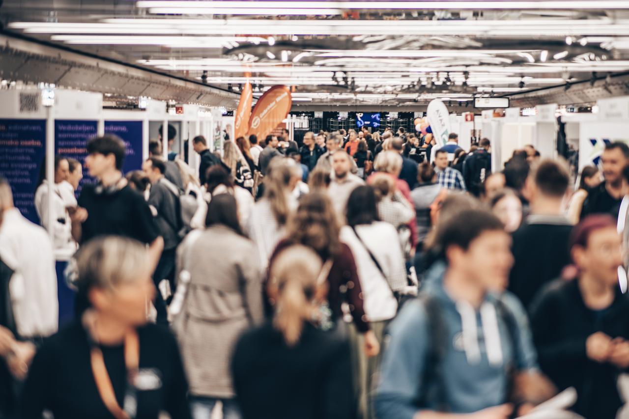 Visitors walk through a crowded career or recruitment fair featuring exhibition booths and company stands. (Adobe Stock Photo)