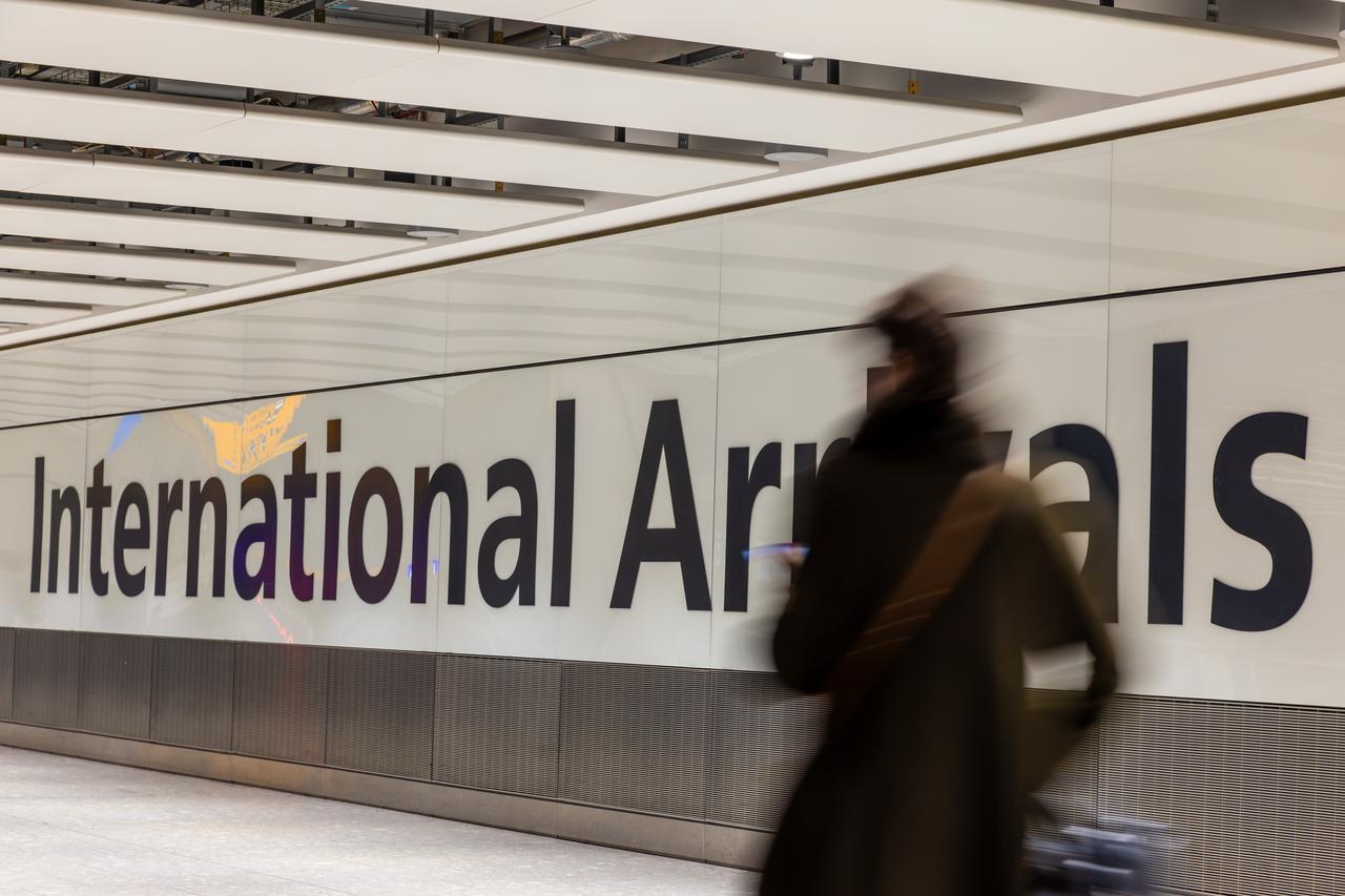 A traveler walks through an international arrivals area at an airport. (Adobe Stock Photo)