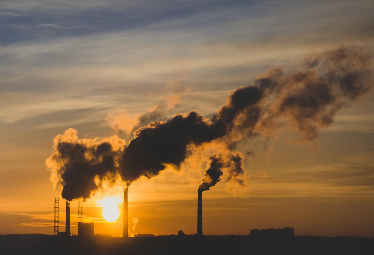 Smoke rises from industrial chimneys at sunset, illustrating emissions linked to air pollution and the formation of ground-level ozone. (Adobe Stock Photo)