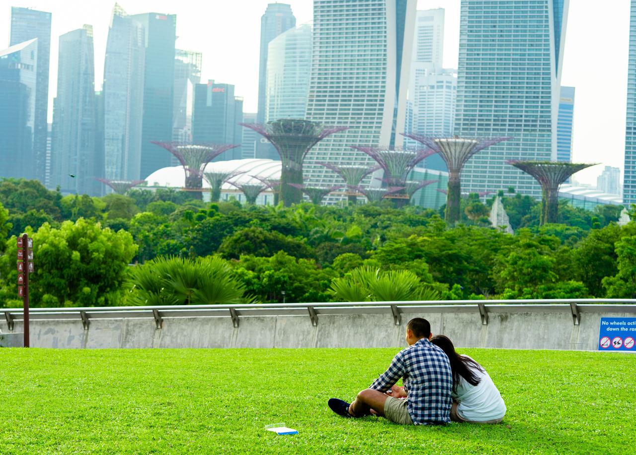 Couples sitting in the garden and looking at the garden by the bay at Marina Barrage, Singapore. (Photo via Adobe Stock)
