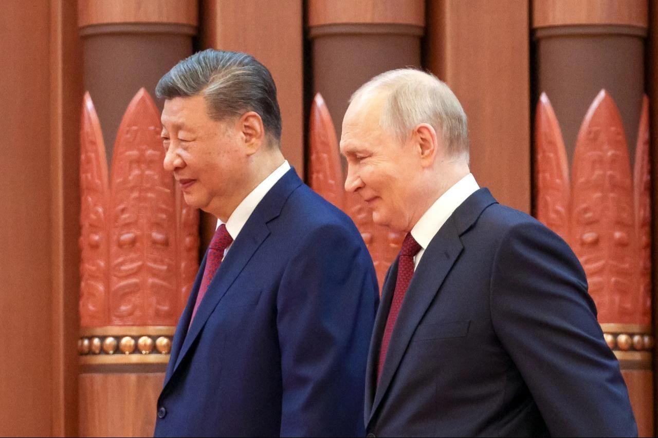 In this pool photograph distributed by the Russian state agency Sputnik, Russia's President Vladimir Putin (R) walks with China's President Xi Jinping as they meet in Beijing, China, May 20, 2026. (Photo by Sputnik/AFP)