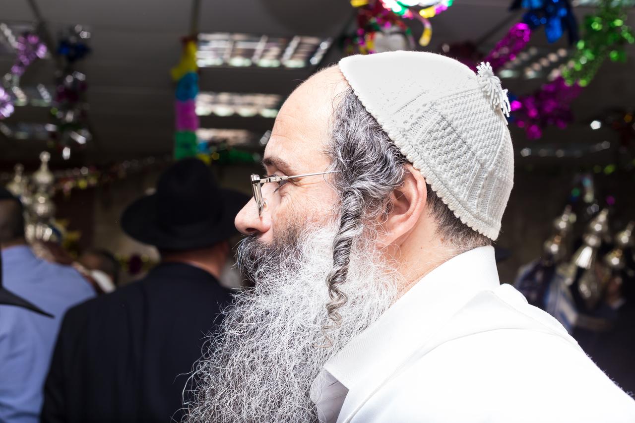 A bearded man wearing a knitted skullcap and sidelocks is pictured during a religious gathering.(Adobe Stock Photo)