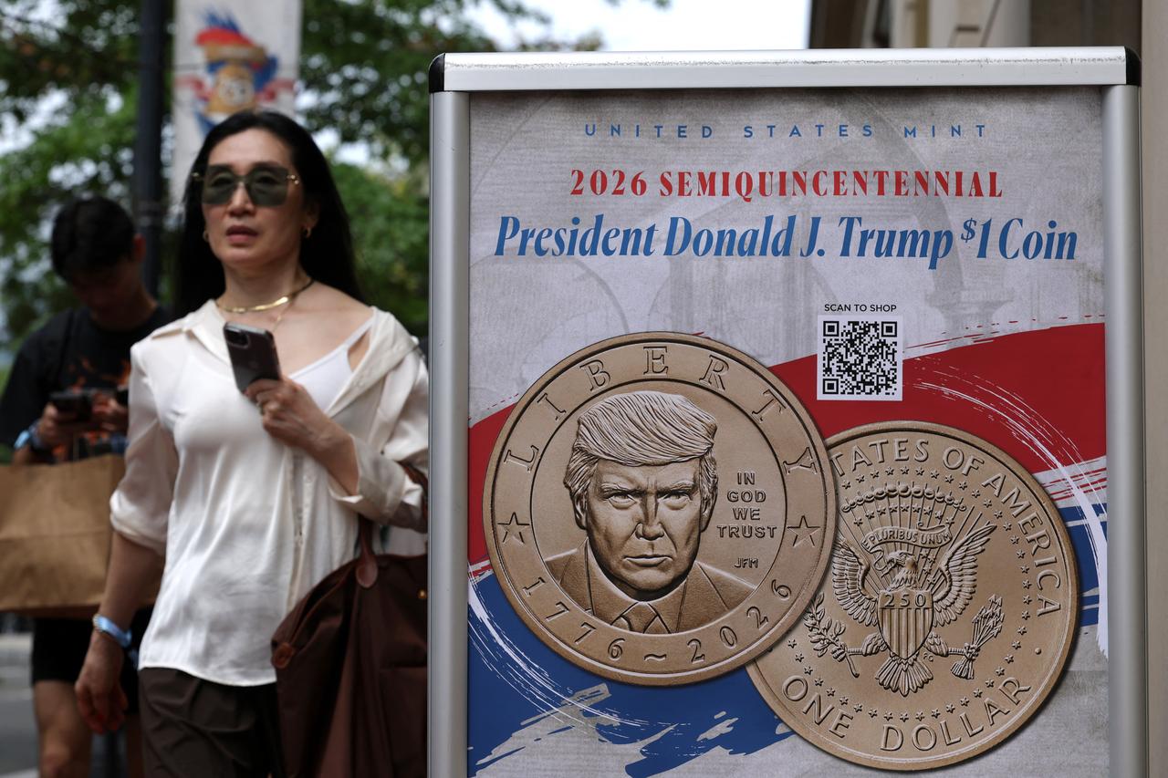 A pedestrian passes by a poster that promotes the newly minted Donald Trump $1 coin outside the U.S Mint Coin Store in Washington, on September 3, 2026. (AFP Photo)