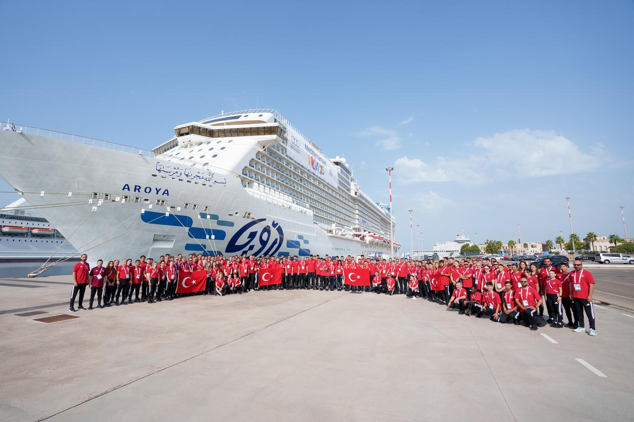 Team Türkiye athletes and officials pose with Turkish flags in front of the Aroya cruise ship during celebrations marking Türkiye’s Victory Day in Taranto, Italy, Aug. 30, 2026. (AA Photo)