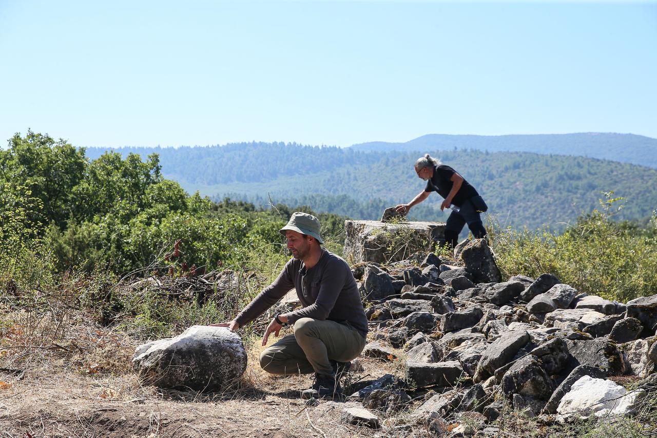 Archaeologists examine stone remains at the site of the ancient city of Hadrianoutherai, founded by Roman Emperor Hadrian in an area associated with his hunting expeditions, in Balıkesir, Türkiye, Sept. 5, 2026. (AA Photo)