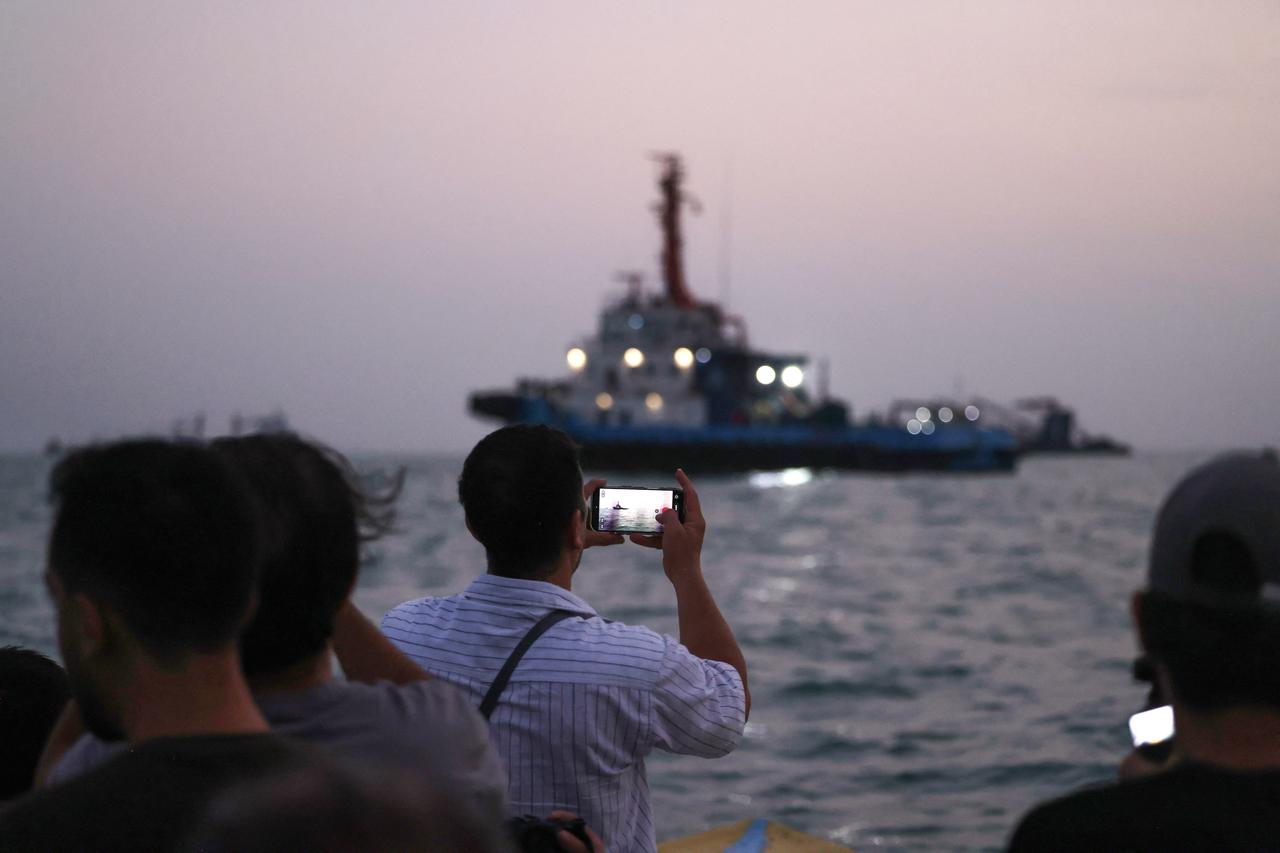 People on a boat take pictures of vessels as they transit the Strait of Hormuz off the coast of the port city of Bandar Abbas in southern Iran on September 5, 2026. (AFP Photo)