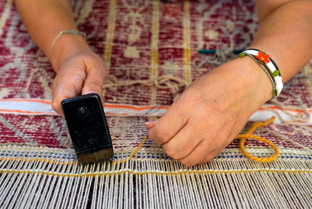 A close-up shows conservation work being carried out on the edge of a historic woven carpet. (AA Photo)