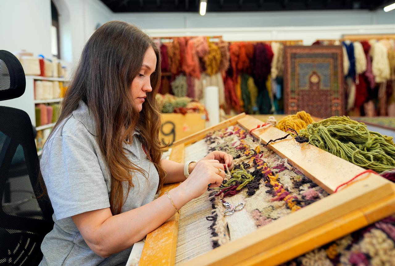 A specialist works on a historic carpet using traditional materials and techniques at the National Palaces restoration workshop. (AA Photo)