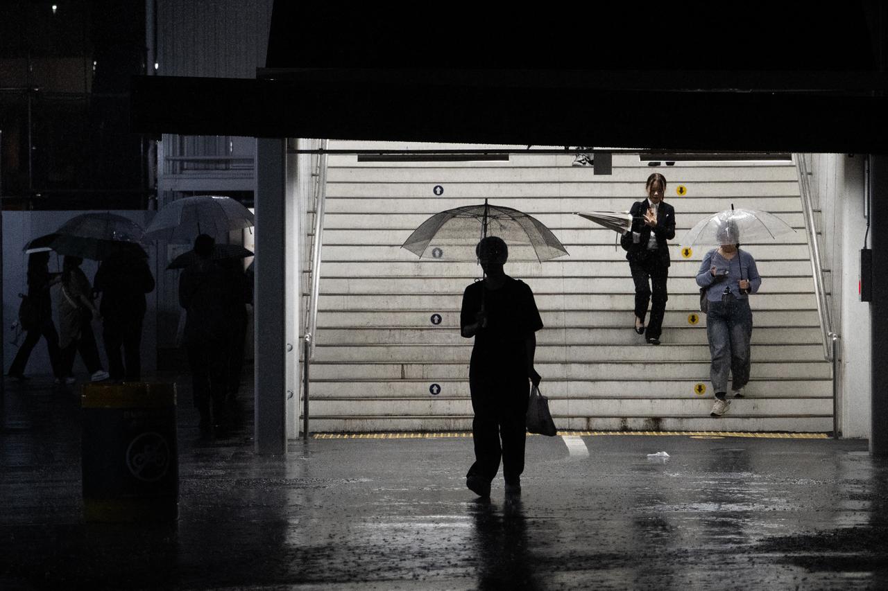 Commuters exit a train station during a heavy rainstorm in Tokyo on September 6, 2026. (AFP Photo)