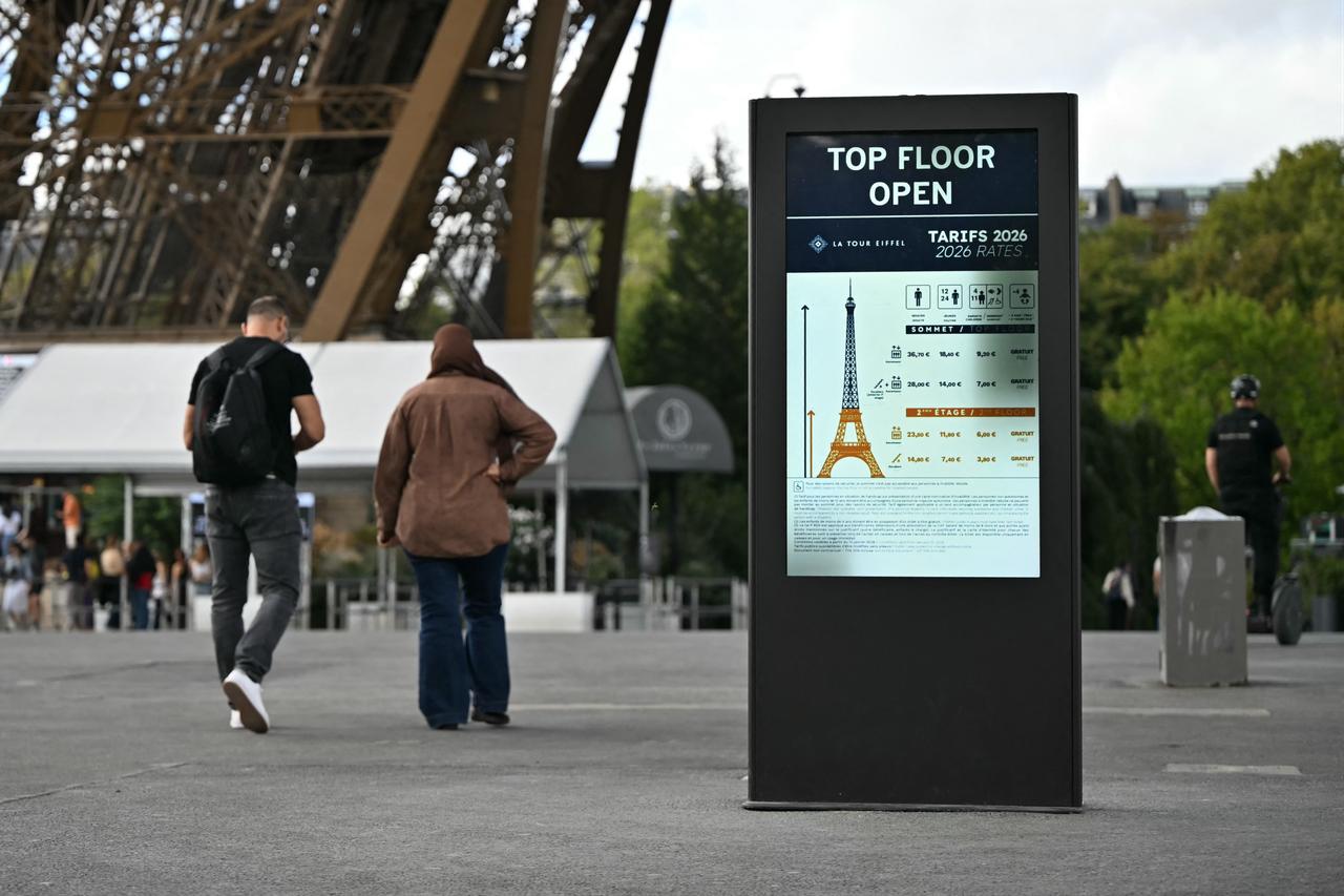 Visitors walk past a sign displaying Eiffel Tower opening information and 2026 ticket prices in Paris, France, Sept. 8, 2026. (AFP Photo)