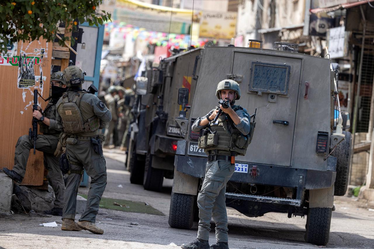 An Israeli army soldier points a rifle while standing before armoured vehicles during an Israeli military operation, east of Nablus in the Israeli-occupied West Bank, Aug. 31, 2026. (AFP Photo)