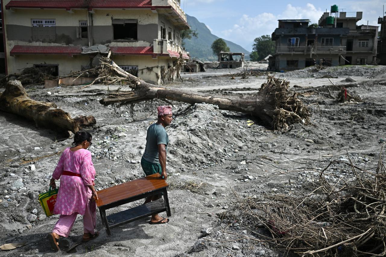 Residents carry furniture through an area devastated by flash floods in Nepal’s Nuwakot district, Sept. 8, 2026. (AFP Photo)