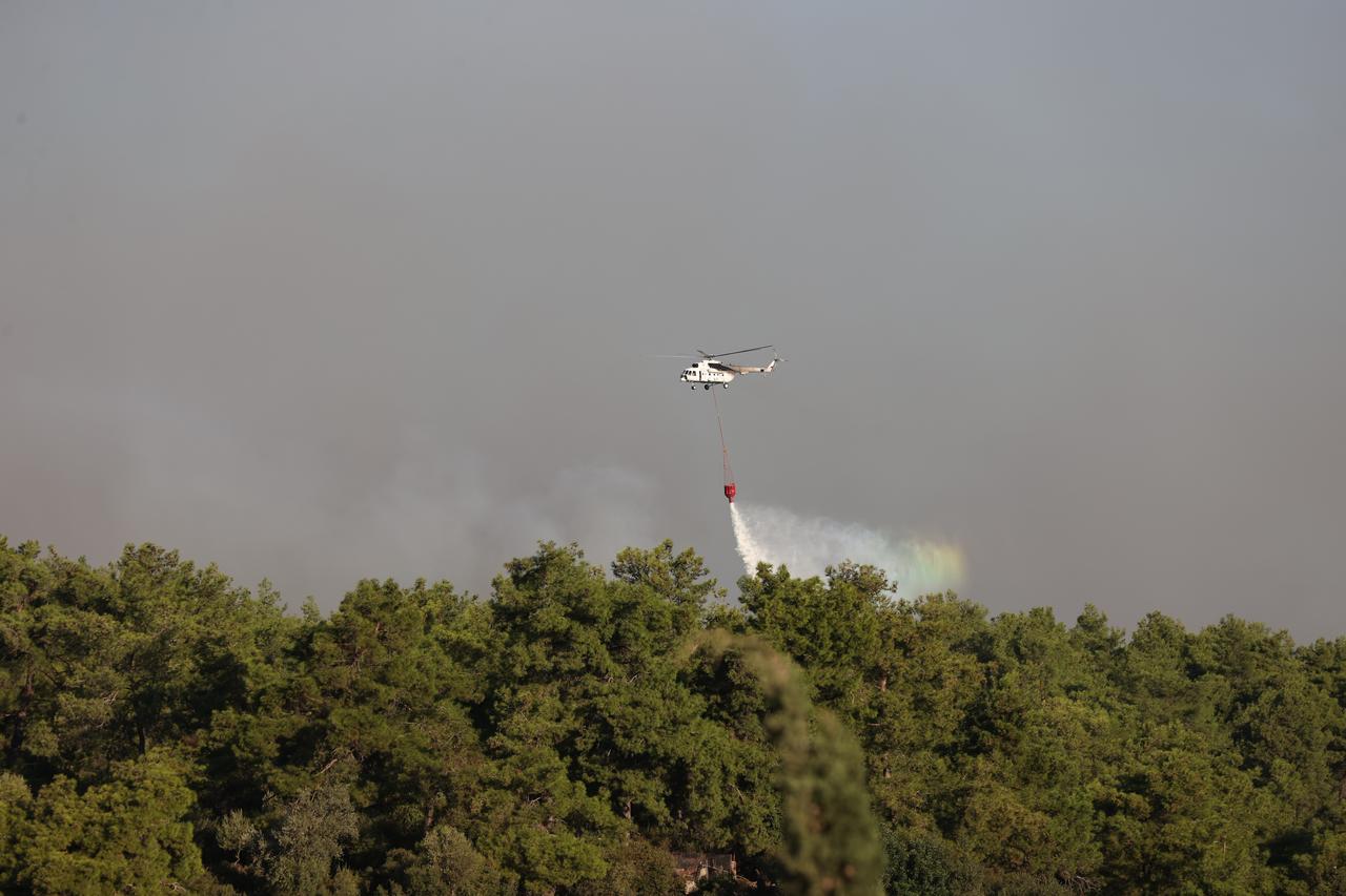 A firefighting helicopter drops water over a forest fire in Antalya, Türkiye, as aerial operations continue to contain the blaze. (AA Photo)