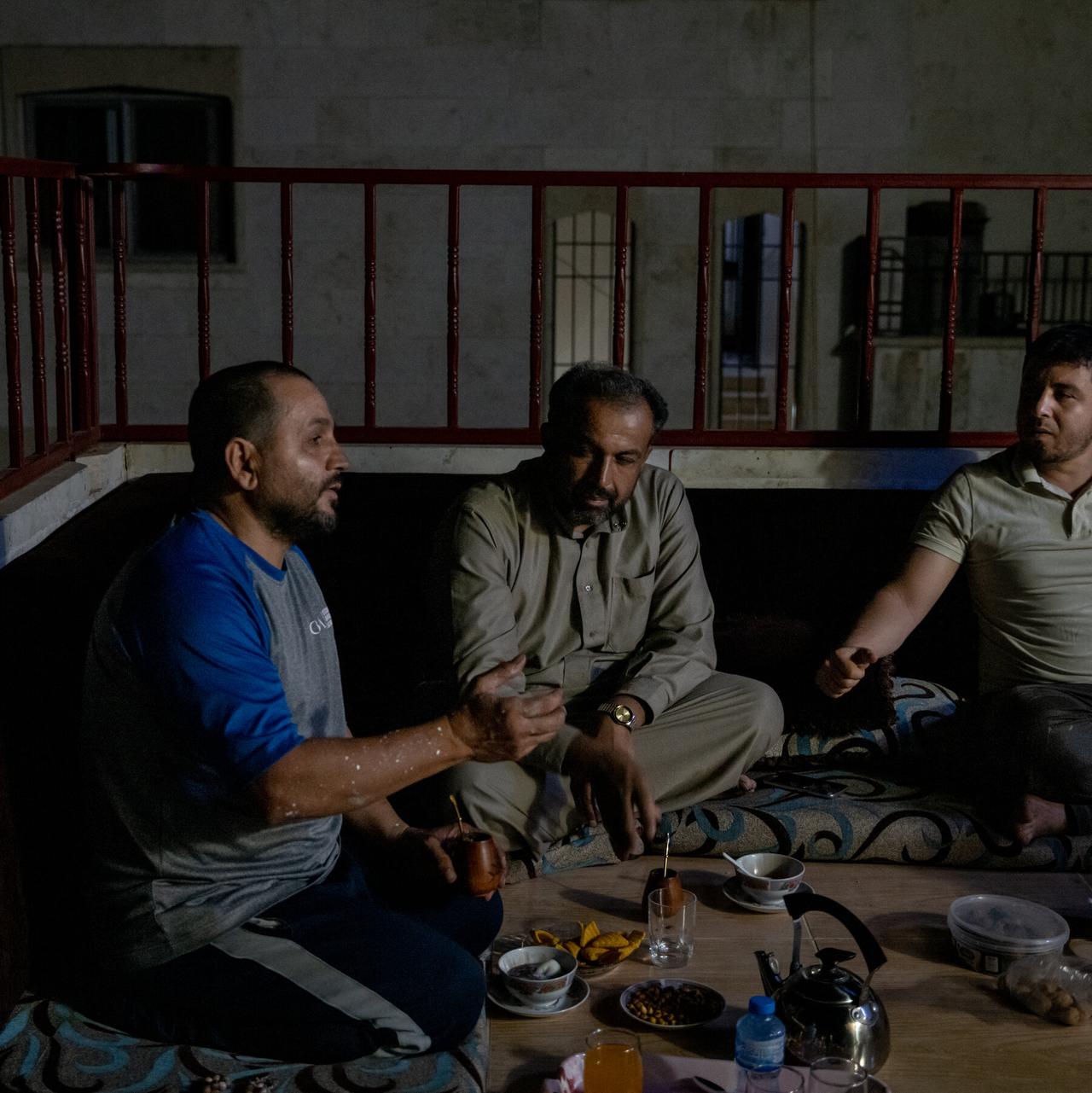 Aziz al-Asmar, left, with friends sharing mate at his home in Binnish, Syria. (Photo by Nicole Tung for The New York Times)