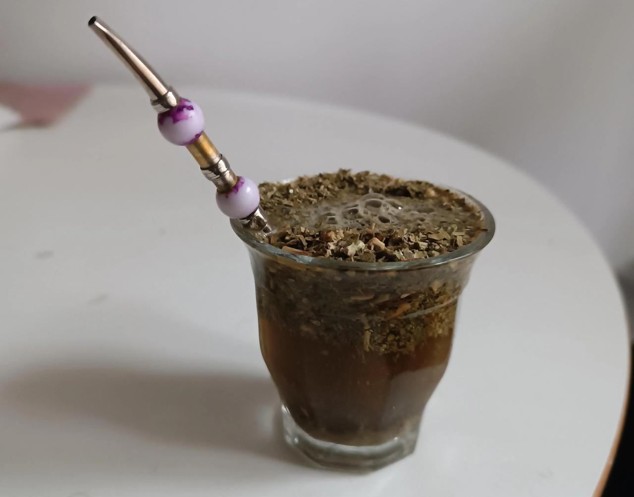 A glass of yerba mate prepared in the Syrian style, with dried leaves and a metal straw. (Photo via Reddit)